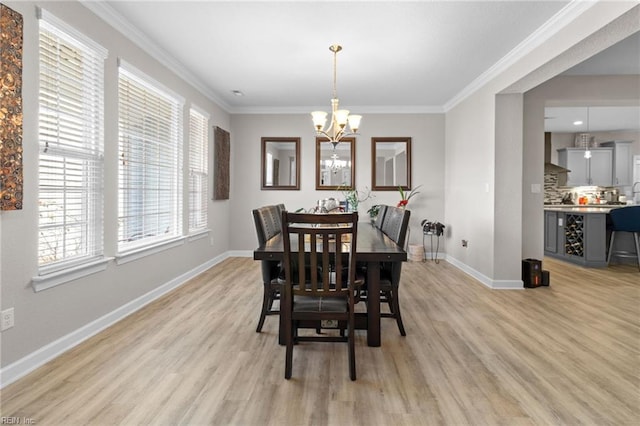 dining space featuring ornamental molding, light wood-type flooring, and a notable chandelier