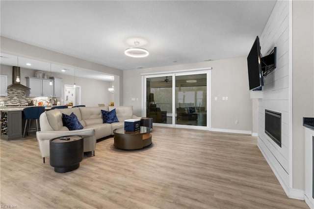 living room featuring baseboards, a fireplace, and light wood-style floors