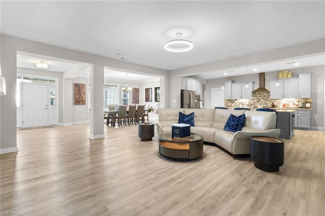 living area with light wood-type flooring, baseboards, and a notable chandelier