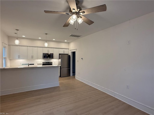 kitchen featuring stainless steel appliances, visible vents, light wood-style floors, white cabinetry, and a peninsula