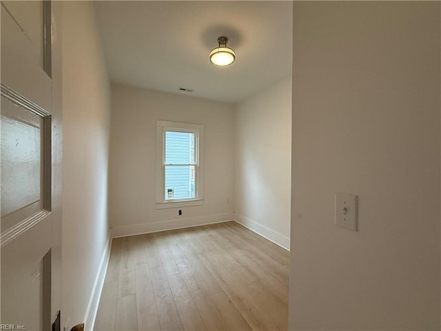 spare room featuring wood finished floors, visible vents, and baseboards