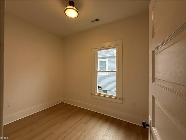 empty room featuring visible vents, baseboards, and wood finished floors