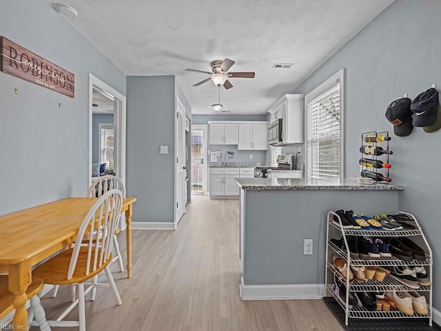 kitchen with stainless steel appliances, white cabinets, visible vents, and light wood-style flooring