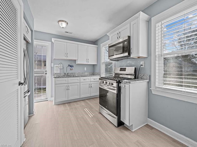 kitchen featuring visible vents, appliances with stainless steel finishes, white cabinets, and baseboards