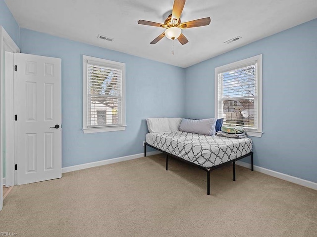 carpeted bedroom with visible vents, baseboards, and multiple windows