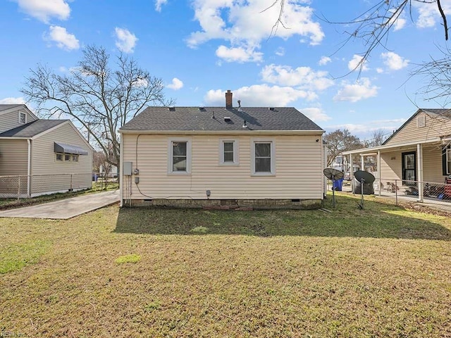 back of house featuring crawl space, a chimney, fence, and a lawn