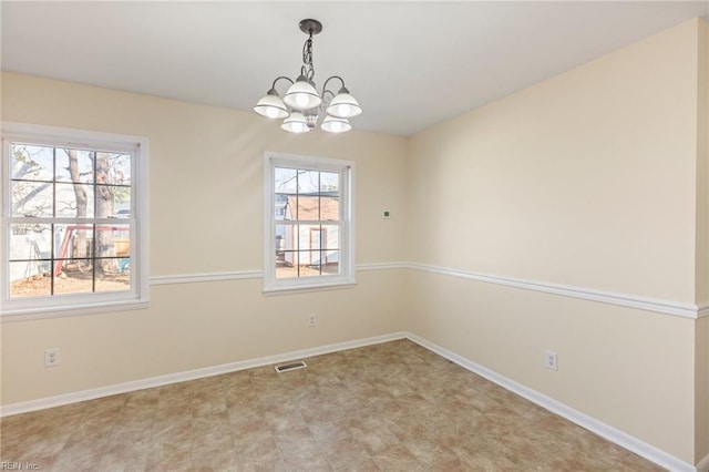 spare room with a healthy amount of sunlight, baseboards, visible vents, and a notable chandelier