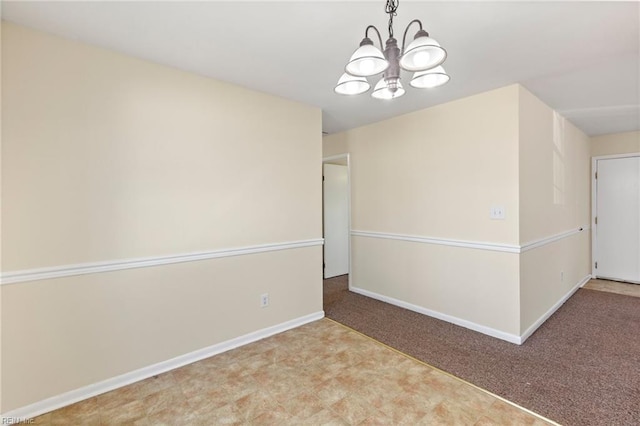 carpeted empty room with baseboards and an inviting chandelier