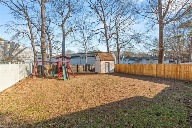 view of yard with a playground, a storage unit, an outdoor structure, and a fenced backyard