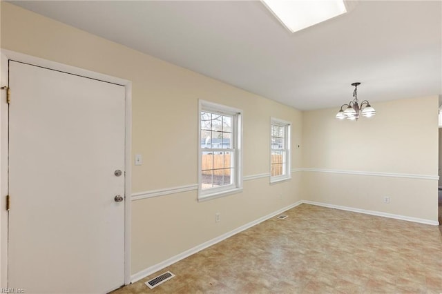 spare room featuring visible vents, a notable chandelier, and baseboards