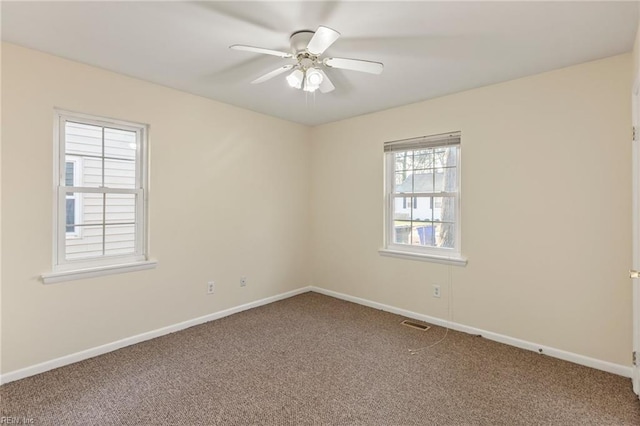 spare room with carpet floors, visible vents, ceiling fan, and baseboards