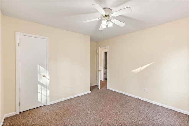 carpeted empty room with ceiling fan and baseboards