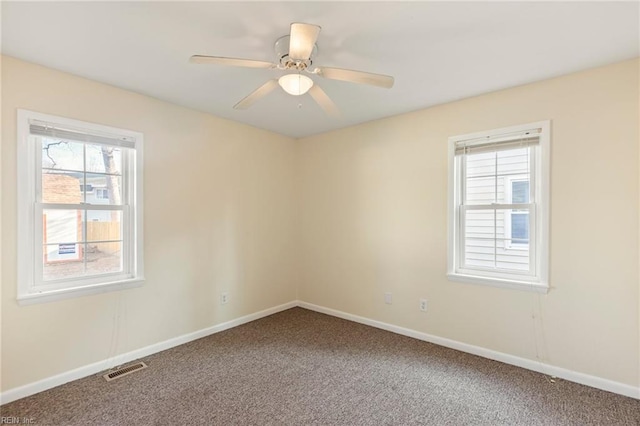 spare room with carpet floors, baseboards, visible vents, and a ceiling fan