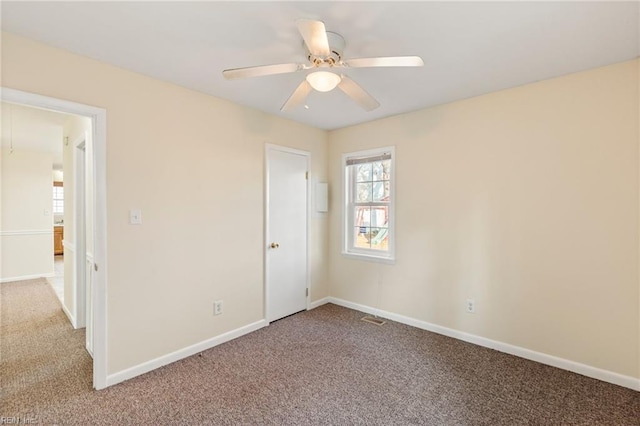 carpeted empty room featuring visible vents, ceiling fan, and baseboards