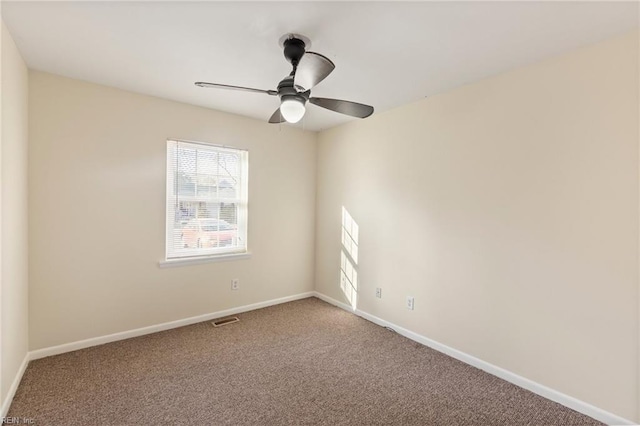 carpeted spare room with visible vents, ceiling fan, and baseboards