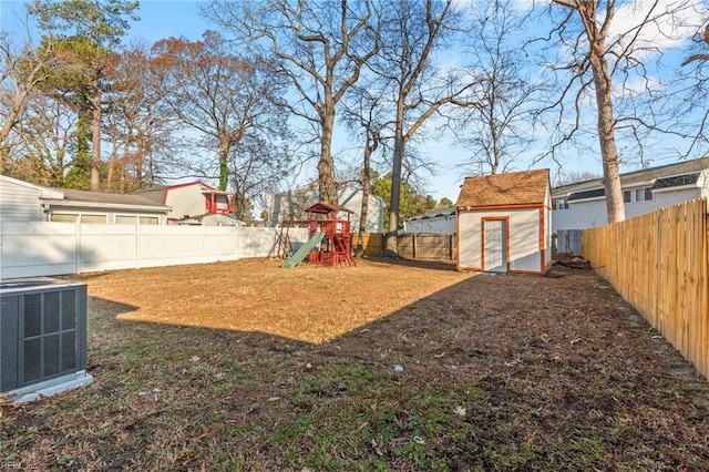 view of yard with a fenced backyard, an outbuilding, a storage unit, cooling unit, and a playground