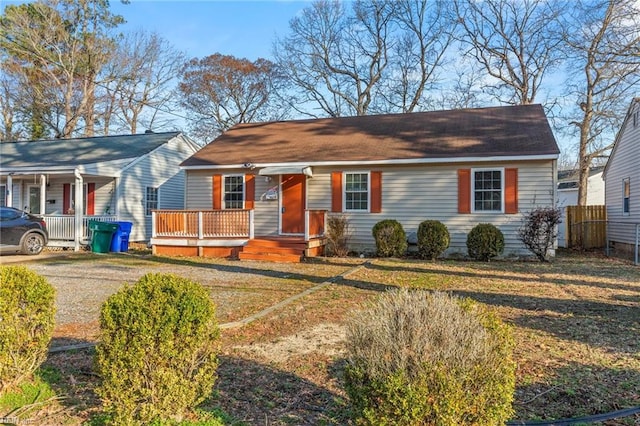 view of front of house with covered porch, a front yard, and fence