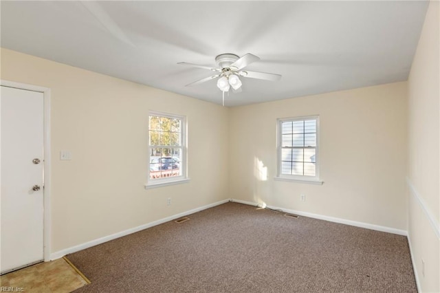 carpeted empty room featuring baseboards, a ceiling fan, and a healthy amount of sunlight