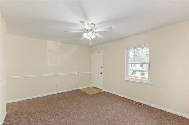 carpeted spare room featuring baseboards, visible vents, and ceiling fan