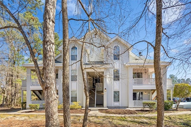 view of front of house with stairway, a porch, and stucco siding