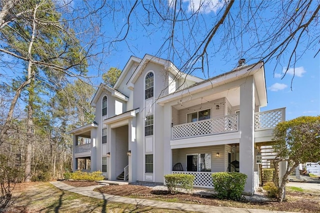 view of front facade featuring a porch, a balcony, and stairs