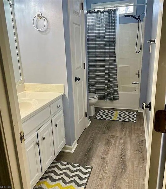 bathroom with shower / bath combo, vanity, toilet, and wood finished floors