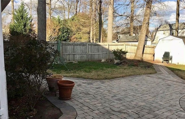 view of patio / terrace with a fenced backyard, a storage unit, and an outbuilding