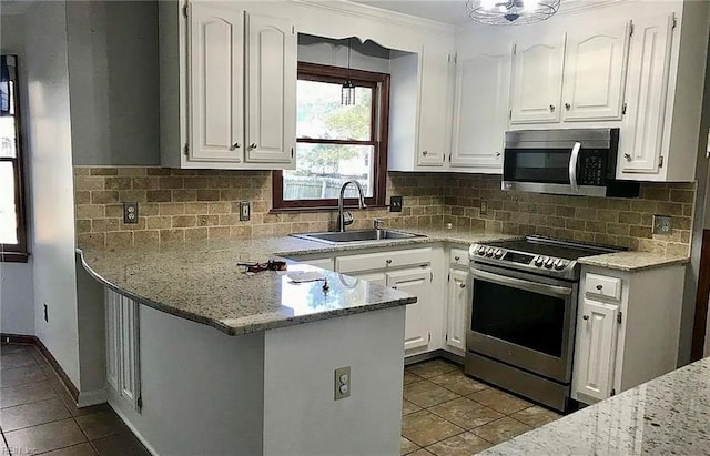 kitchen featuring a peninsula, appliances with stainless steel finishes, a sink, and white cabinets