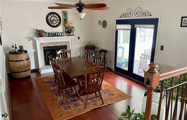 dining area with a fireplace with raised hearth, ceiling fan, and hardwood / wood-style flooring