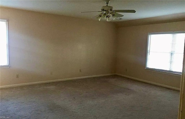 carpeted spare room featuring ceiling fan and baseboards