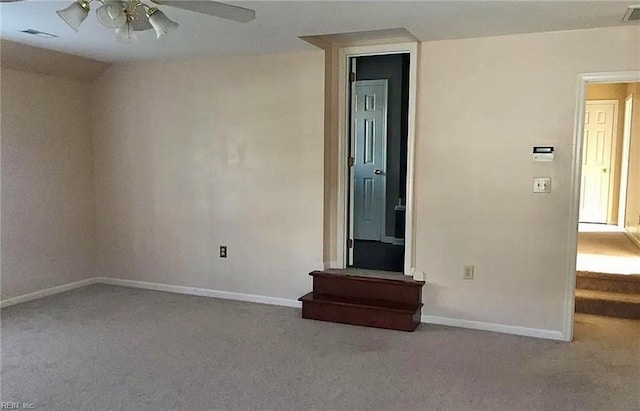 carpeted spare room featuring a ceiling fan, visible vents, and baseboards