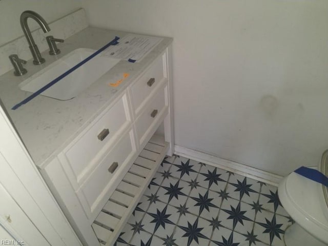 bathroom featuring toilet, vanity, baseboards, and tile patterned floors