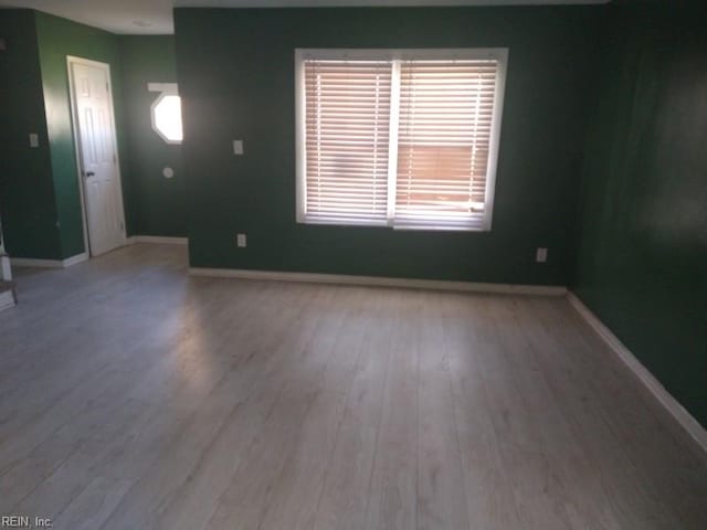 spare room with baseboards and wood finished floors