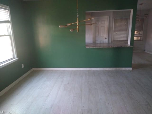 empty room with baseboards, wood finished floors, and a healthy amount of sunlight