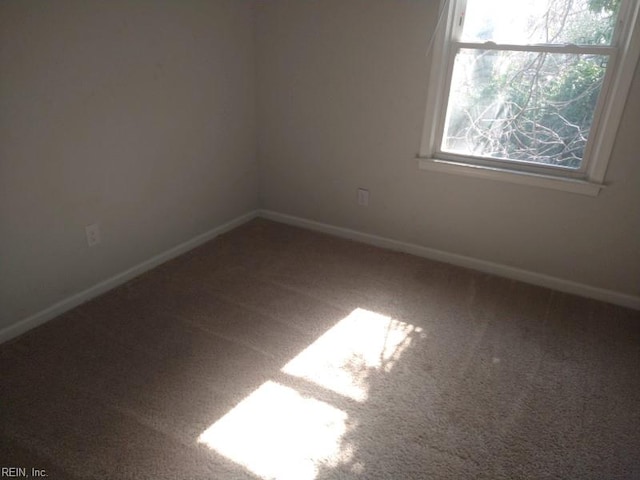 carpeted spare room featuring baseboards