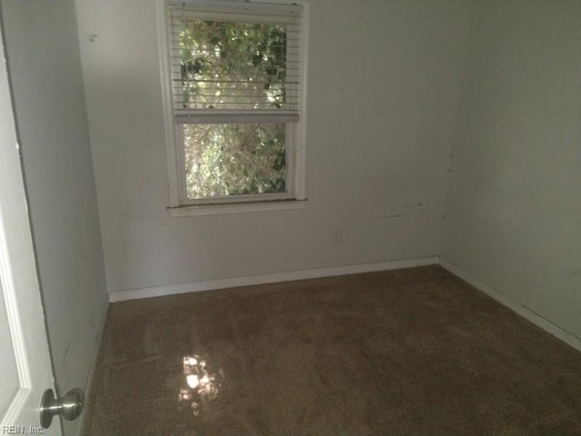 spare room featuring carpet floors and baseboards