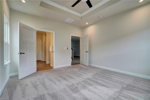 unfurnished bedroom with recessed lighting, a raised ceiling, baseboards, and carpet floors