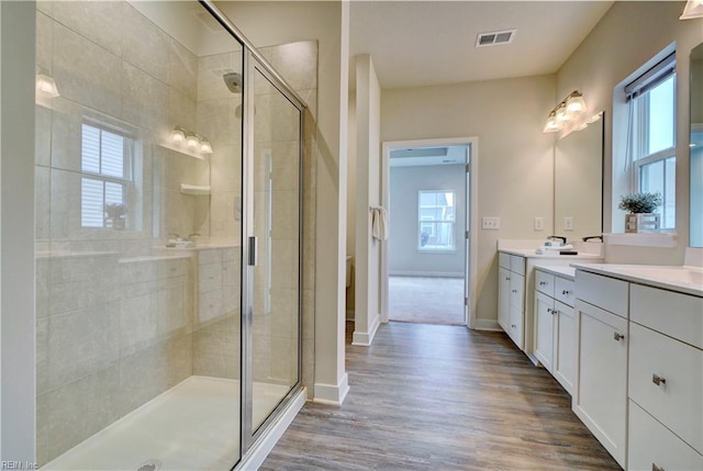 bathroom featuring visible vents, vanity, wood finished floors, and a shower stall