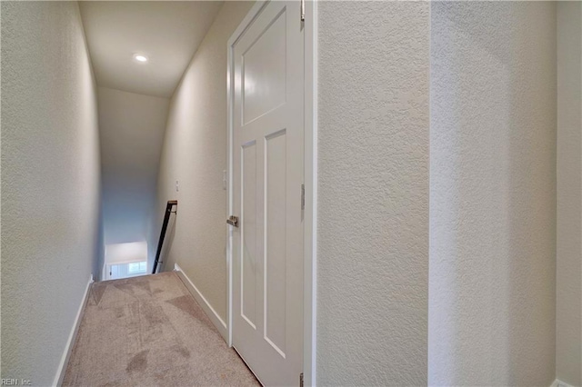 hall featuring visible vents, an upstairs landing, carpet flooring, baseboards, and a textured wall