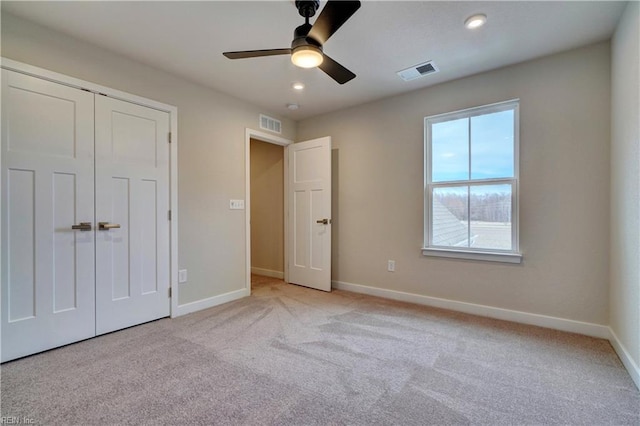 unfurnished bedroom with visible vents, baseboards, light colored carpet, and a closet