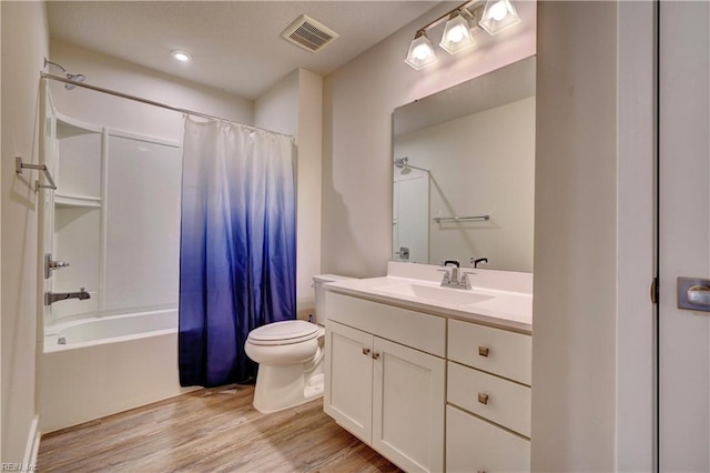 bathroom featuring visible vents, toilet, wood finished floors, shower / bath combination with curtain, and vanity