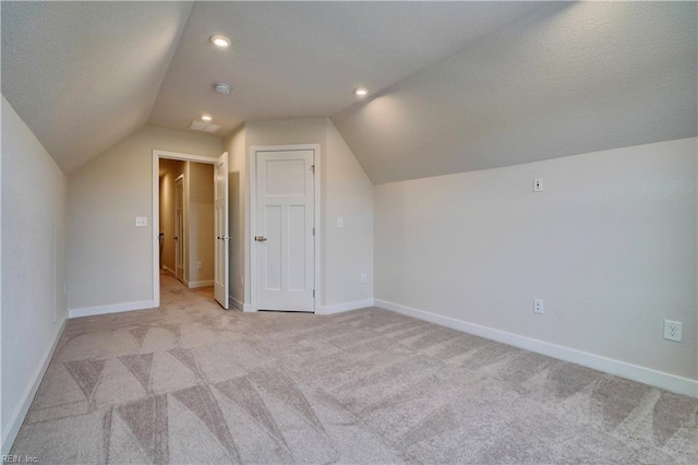 bonus room featuring a textured ceiling, vaulted ceiling, baseboards, and light carpet