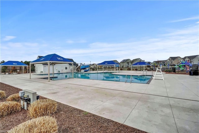 pool featuring a residential view, a water slide, a patio, and fence