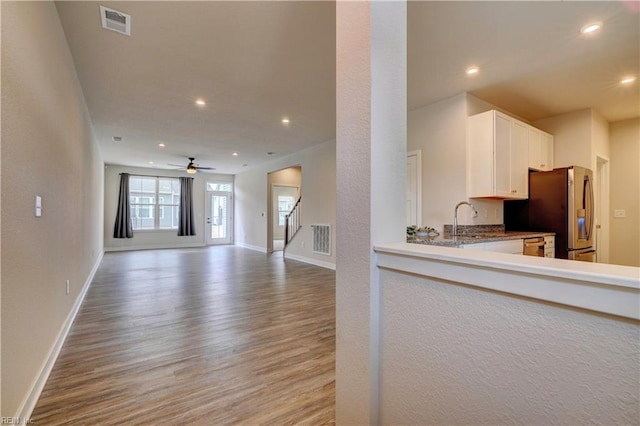 kitchen with wood finished floors, white cabinets, recessed lighting, and stainless steel fridge with ice dispenser