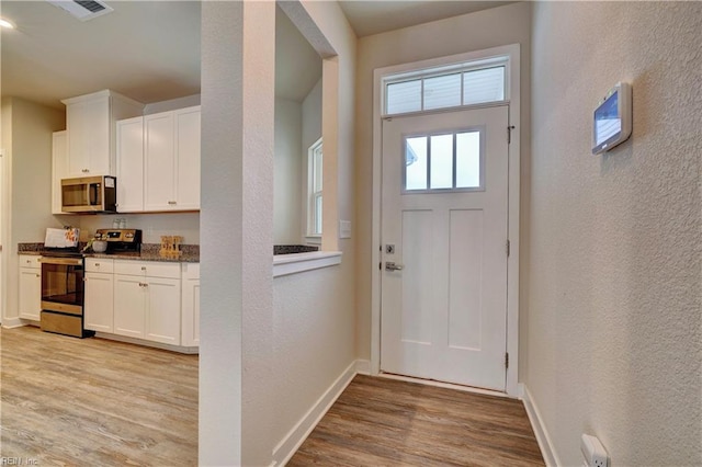 entrance foyer featuring visible vents, light wood-style flooring, baseboards, and a textured wall