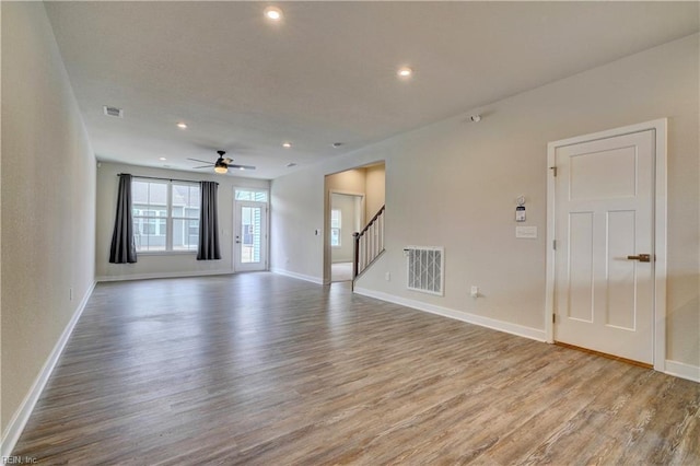 unfurnished living room featuring recessed lighting, stairway, baseboards, and wood finished floors