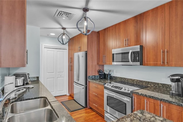 kitchen featuring stainless steel appliances, a sink, visible vents, and brown cabinets