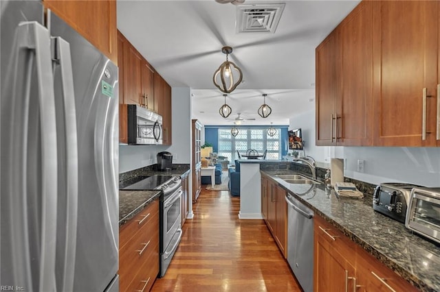 kitchen featuring brown cabinetry, visible vents, stainless steel appliances, and wood finished floors