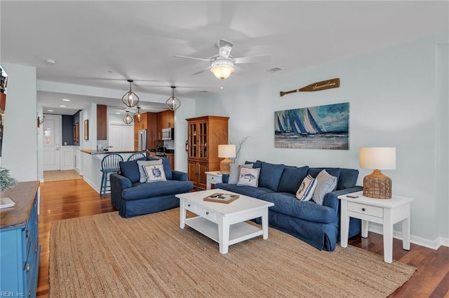 living area with visible vents, ceiling fan, and wood finished floors