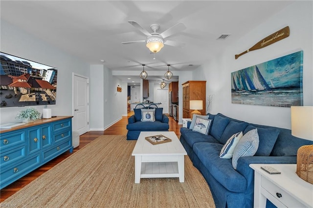 living area featuring dark wood-style flooring, visible vents, ceiling fan, and baseboards